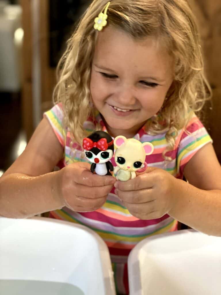 Little girl smiling and looking at Baby born surprise pets