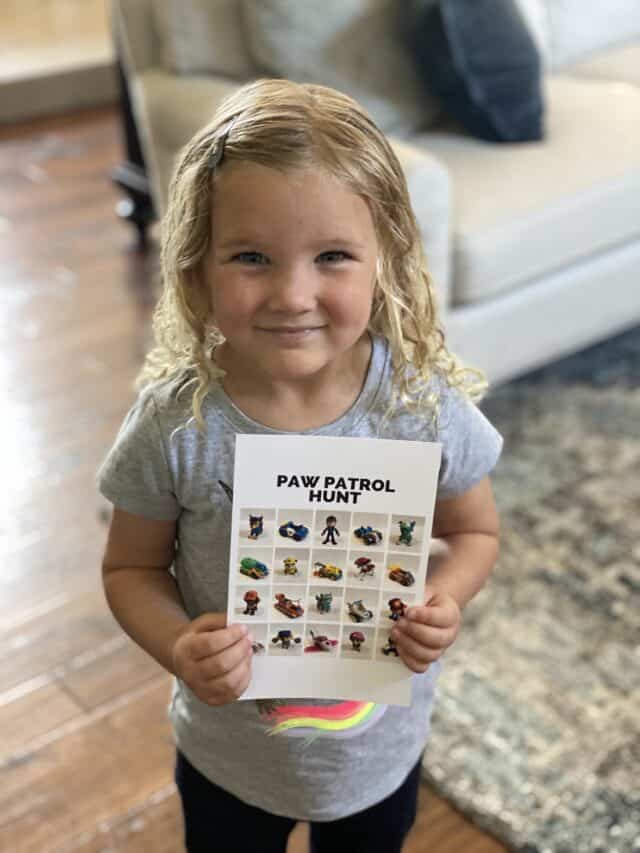 girl smiling holding a Paw Patrol scavenger hunt card