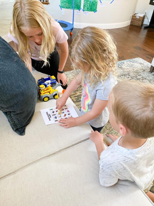 two girls and one boy leaning on a couch, writing on a piece of paper